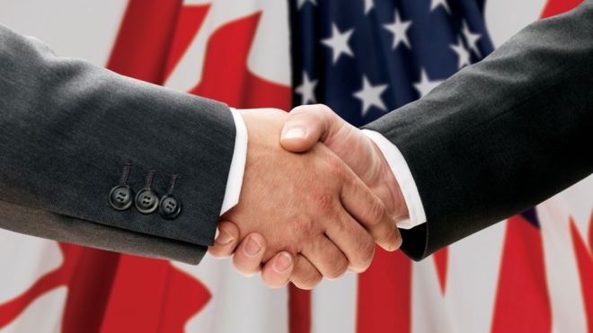 handshake with Canada and US flag in the background